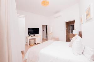 a white bedroom with a white bed and a television at Giorgio Boutique Hotel in Sliema