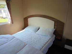 a bedroom with a bed with white sheets and a window at Highfield and Haven : Elegance:- 4 Berth Central Heated in Lincolnshire