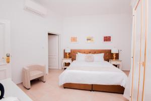a white bedroom with a bed and a chair at Giorgio Boutique Hotel in Sliema
