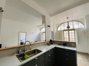una cucina con lavandino e grande specchio di Appartement dans belle résidence Semuroise a Semur-en-Auxois