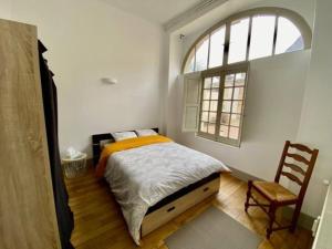 una camera con letto, finestra e sedia di Appartement dans belle résidence Semuroise a Semur-en-Auxois