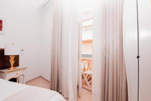 a bedroom with white curtains and a table and a chair at Giorgio Boutique Hotel in Sliema