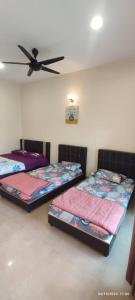two beds in a room with a ceiling fan at Comfy room in Gunung Ledang 