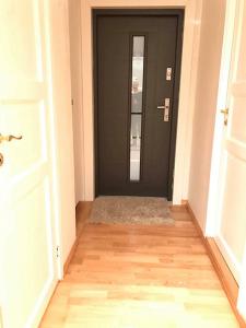 einen Flur mit schwarzer Tür und Holzboden in der Unterkunft Apartment in Åsane in Bergen