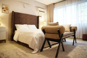 ein Schlafzimmer mit einem Bett, einem Stuhl und einem Fenster in der Unterkunft Ruby and Pearl by Flair Apartments in Lagos