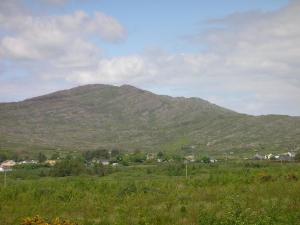 een berg in de verte met een groen veld bij Tearmann Solais in Schull