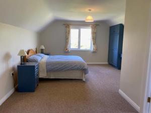 a bedroom with a blue bed and a window at Tearmann Solais in Schull