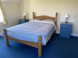 - une chambre avec un lit en bois et 2 tables de nuit bleues dans l'établissement Tearmann Solais, à Schull