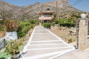 a walkway leading to a house with mountains in the background at Villa Kyma by the sea, in South Crete in Keratokampos