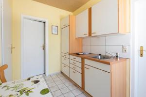 een kleine keuken met witte kasten en een wastafel bij Villa Regina Waldblick in Friedrichroda
