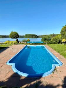 a blue swimming pool with a lake in the background at Mazury na Śląsku - Dom Wakacyjny z basenem in Boguchwałowice