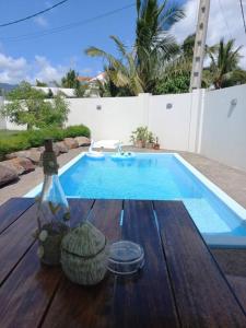 a swimming pool with a wooden table next to a swimming pool at Bois Mapou Self Catering Apartments Unit 203 in Rivière Noire