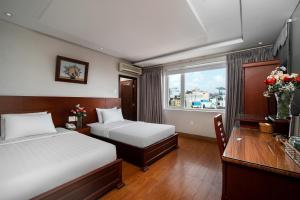 Van Ha Hotel في مدينة هوشي منه: غرفة نوم بسريرين ومكتب ونافذة