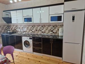 a kitchen with white cabinets and a washer and dryer at Mountain Resort House in Gabala