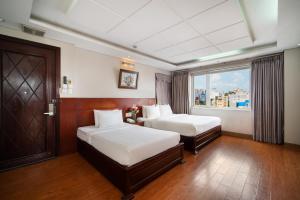 a hotel room with two beds and a window at Van Ha Hotel Etown - Nhà Ga T3 Sân Bay TSN in Ho Chi Minh City