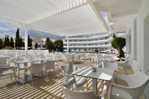 restauracja z białymi stołami i krzesłami oraz budynek w obiekcie Hotel Palia La Roca w mieście Benalmádena