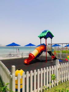 um parque infantil junto à praia com uma cerca branca em نسمة بحر Nesma em Ras al-Khaimah