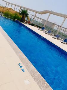 uma grande piscina azul com cadeiras num edifício em نسمة بحر Nesma em Ras al-Khaimah