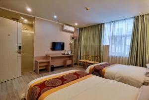 ein Hotelzimmer mit 2 Betten und einem Schreibtisch in der Unterkunft Songyuan Hotel 松缘酒店 in Shenzhen