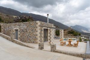 ein Steingebäude mit einem Tisch und Bänken auf einer Terrasse in der Unterkunft Nature Villas Myrthios in Plakias