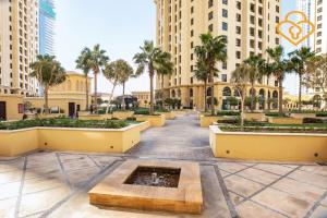 um pátio com uma fonte e palmeiras e edifícios em Keysplease Beachside Studio Minutes to the Beach & The Walk, JBR P50A em Dubai
