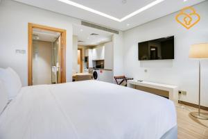 um quarto branco com uma cama e uma televisão em Keysplease Beachside Studio Minutes to the Beach & The Walk, JBR P50A em Dubai