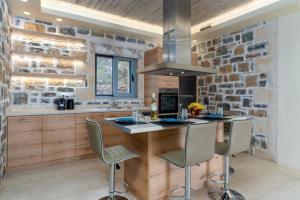 a kitchen with a stone wall and a island with chairs at Nature Villas Myrthios in Plakias