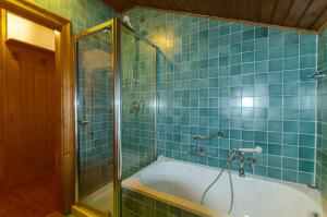 a blue tiled bathroom with a tub and a shower at Spazioso appartamento centrale con wi-fi in Cortina dʼAmpezzo