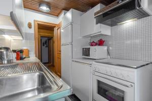 a kitchen with a sink and a white refrigerator at Spazioso appartamento centrale con wi-fi in Cortina dʼAmpezzo