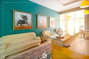a living room with a couch and a painting of a horse at NBT Hotel Reps in Kukës
