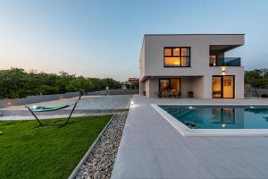 a house with a swimming pool in front of it at Villa Rocinante ZadarVillas in Murvica