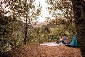 a woman sitting on a blanket next to a tent at INSPIRE Villages - Anduze in Corbés