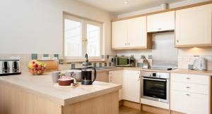 a kitchen with white cabinets and a cake on a counter at Salmon Run Lodge in Carrbridge