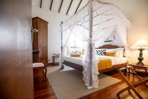 a bedroom with a white canopy bed in a room at Manuel Manor in Labugolla