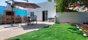 eine Terrasse mit einem Tisch, einem Regenschirm und Gras in der Unterkunft Catita Home in Vila Nova De Cacela