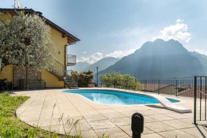 a swimming pool in front of a house with mountains at Casa Acqua in Riva di Solto