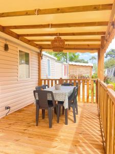 un patio con mesa y sillas en una terraza en Mobil home camping 4 étoiles les Viviers 2 chambres, en Lège-Cap-Ferret