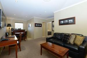 a living room with a black leather couch and a table at Rydges Armidale in Armidale