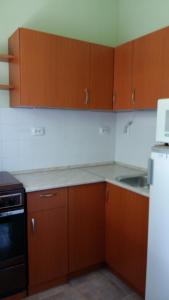 a kitchen with wooden cabinets and a sink and a refrigerator at Szatmári Vendégház in Balatonlelle