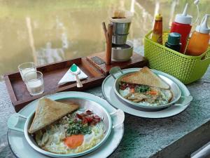 Una mesa cubierta con dos platos de comida con sándwiches. en นิทานคำกลอน 2 Nithankumkon 2, en Amphawa