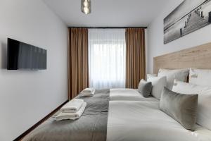 a bedroom with a large bed with two towels on it at Downtown Apartments Seaside Baltea Park & Parking in Gdańsk