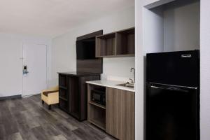 a kitchen with a black refrigerator and a sink at Suburban Studios in Hinesville