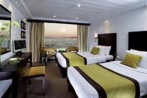 ルクソールにあるPremium Nile Cruise Luxor To Aswan 4Nights started from luxor 3 Nights started from Aswanのベッド2台と大きな窓が備わるホテルルームです。