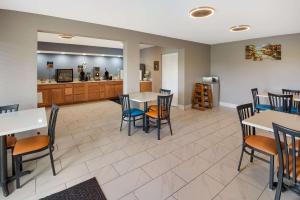 a dining room with tables and chairs and a kitchen at Clarion Pointe Indianapolis Northeast in Castleton
