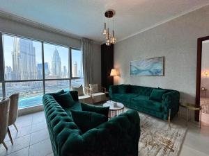 a living room with green couches and a large window at Durrani Homes - Grand 5BR besides Burj khalifa and Fountain view in Dubai