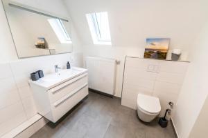 a white bathroom with a sink and a toilet at Hökis-Zimmervermietung 7 in Brande-Hörnerkirchen