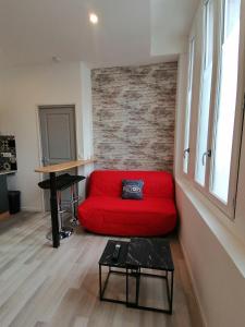 a red couch in a living room with a piano at Studio cosy Brick Home Gare à 100m in Tonneins