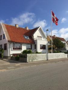 ein weißes Haus mit einem roten Dach und einer Flagge in der Unterkunft Sønderstrand Bed & Breakfast Skagen in Skagen