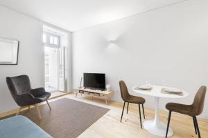 een woonkamer met een tafel en stoelen en een televisie bij InBloom Apartments 3 in Porto