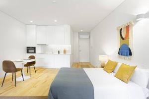 een witte slaapkamer met een groot bed en een keuken bij InBloom Apartments 3 in Porto